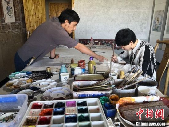 圖為2020年8月下旬，敦煌“80后”畫家張杰龍(左)在為云南麗江“學(xué)生”莫北講解敦煌壁畫的繪畫技巧?！●T志軍 攝