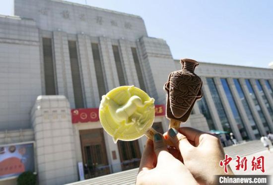 2021年7月30日，游客手拿“銅奔馬”“彩陶瓶”造型的雪糕，在甘肅省博物館前拍照打卡?！「哒?攝