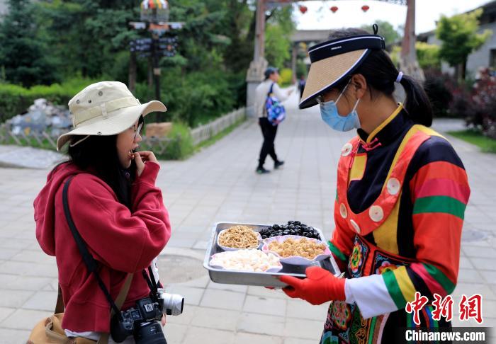 圖為身穿土族服飾的女性介紹當(dāng)?shù)靥厣〕??！⊙Φ?攝