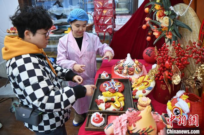 1月25日，隨著春節(jié)臨近，蘭州一花饃店“龍”元素花饃熱銷。圖為工作人員向顧客推薦“龍”元素花饃。九美旦增 攝</p><p>